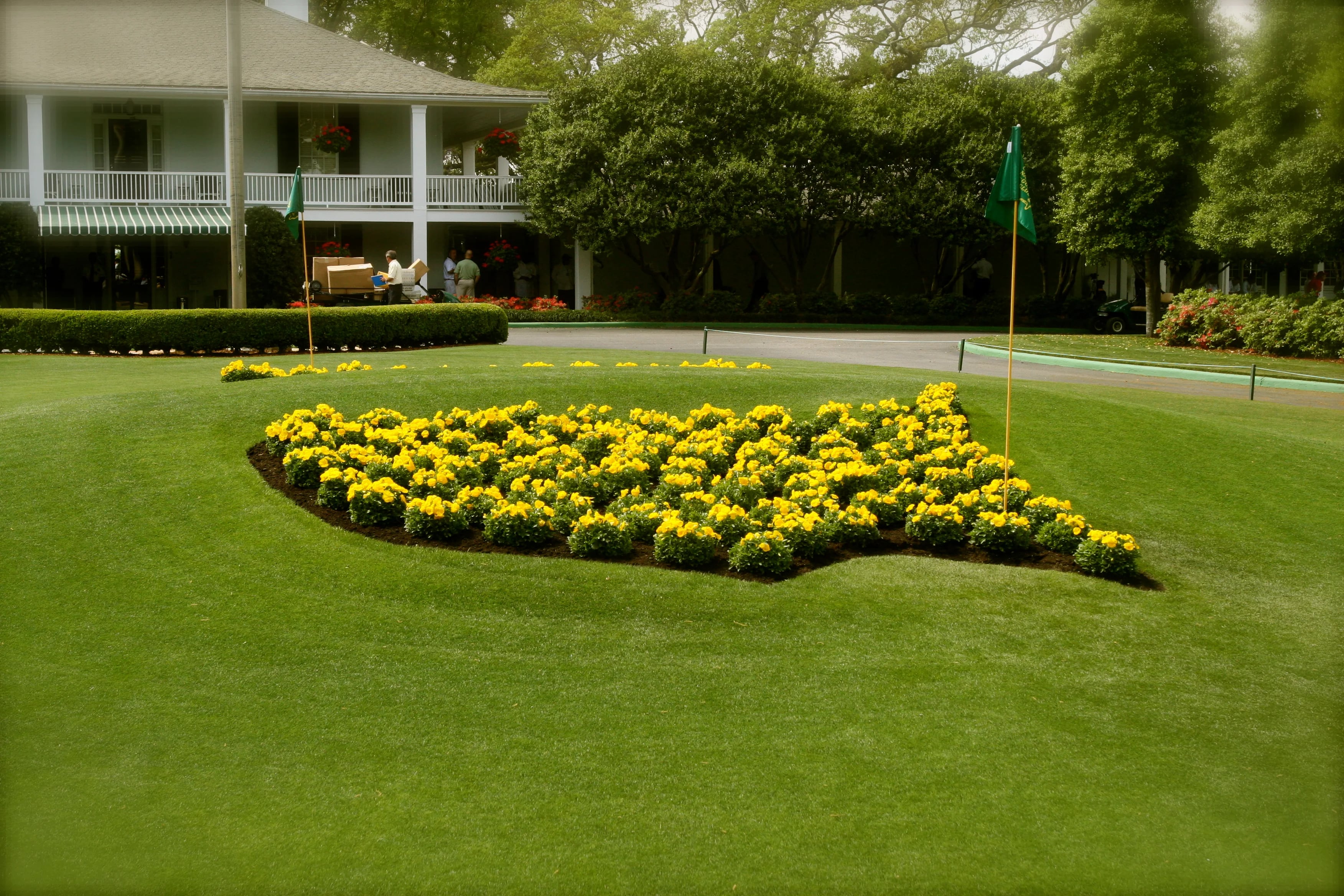 The Masters logo planted in yellow flowers on the lawn in front of the Augusta National clubhouse